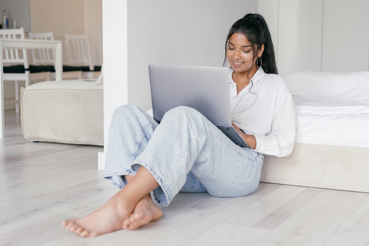 Young lady sitting on the floor looking at her laptop on her lap