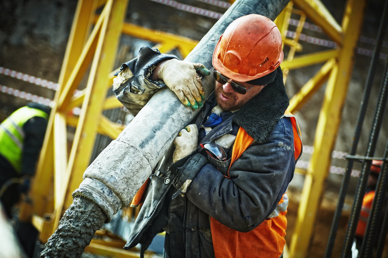Construction worker on a job site holding a large metal pipe