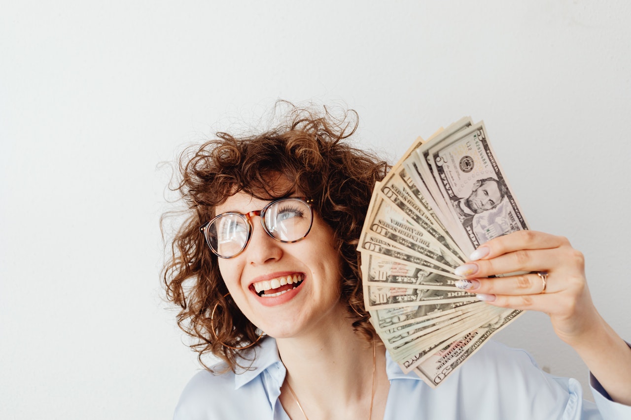 Woman holding up cash bills in her hand with excited look on her face