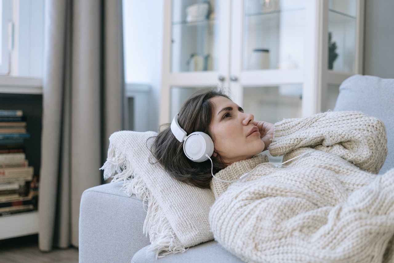 Woman lying on a couch relaxing with headphones on