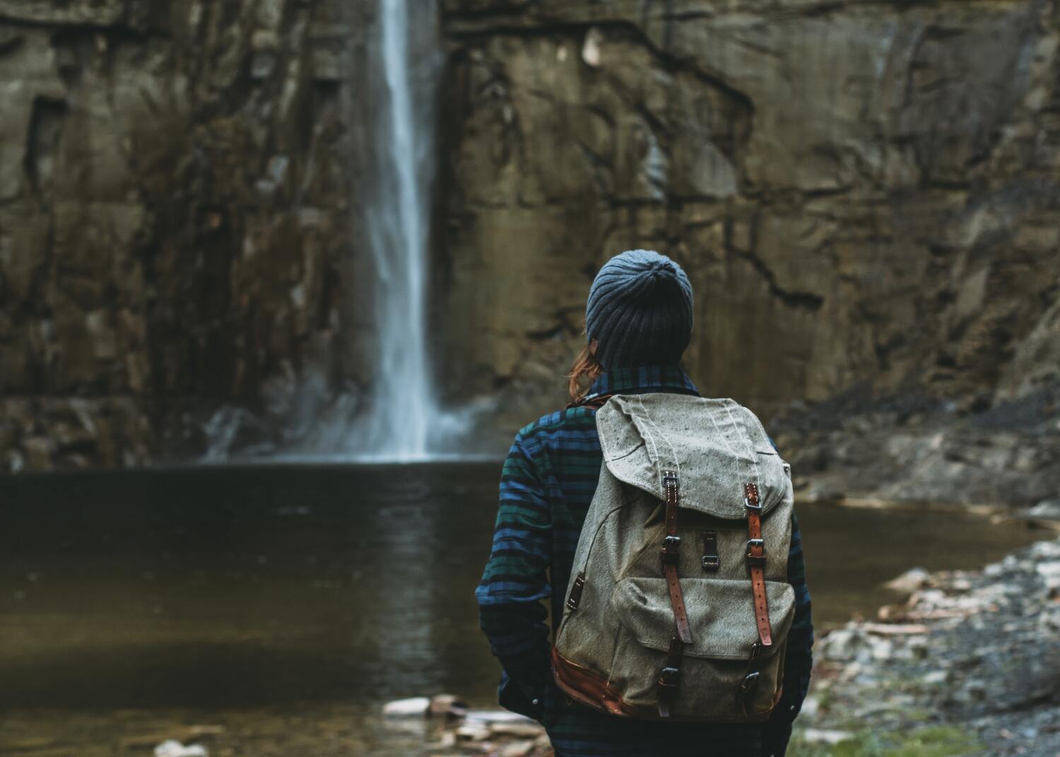 Man with a backpack looking at Upstate New York waterfall.