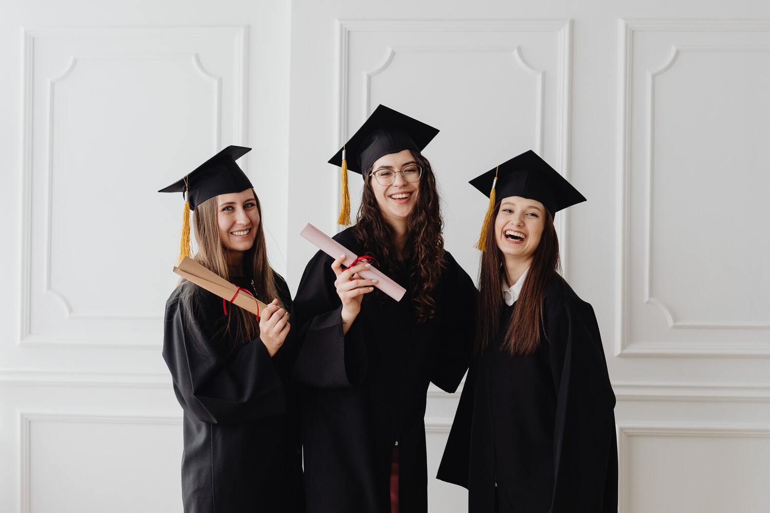Three graduates smiling with diplomas.