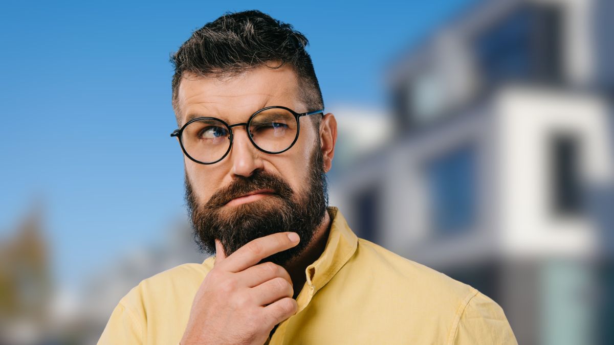 man with glasses in front of houses