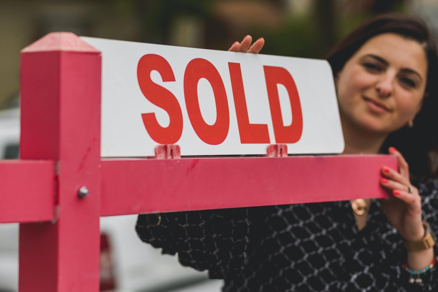 A women buying in a hot housing market with her sold sign.