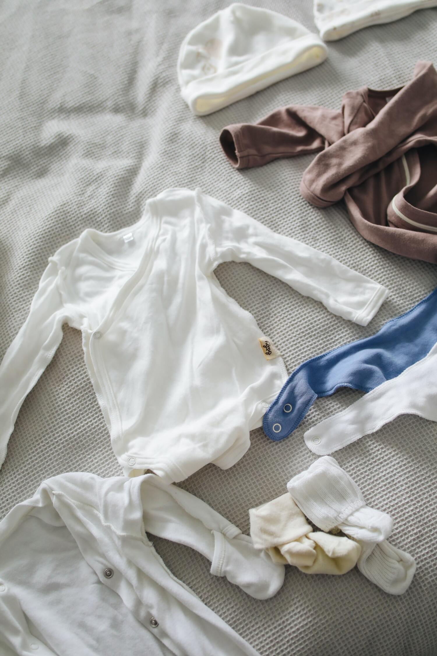 Baby clothes laying on a bed.