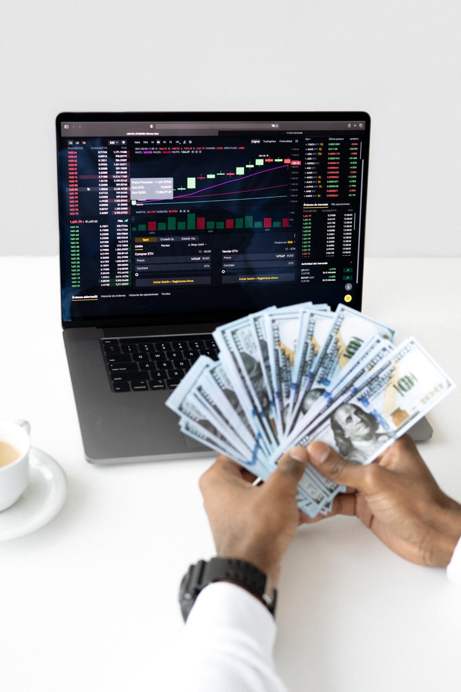 A man with cash in hand and the stock market on his computer screen.