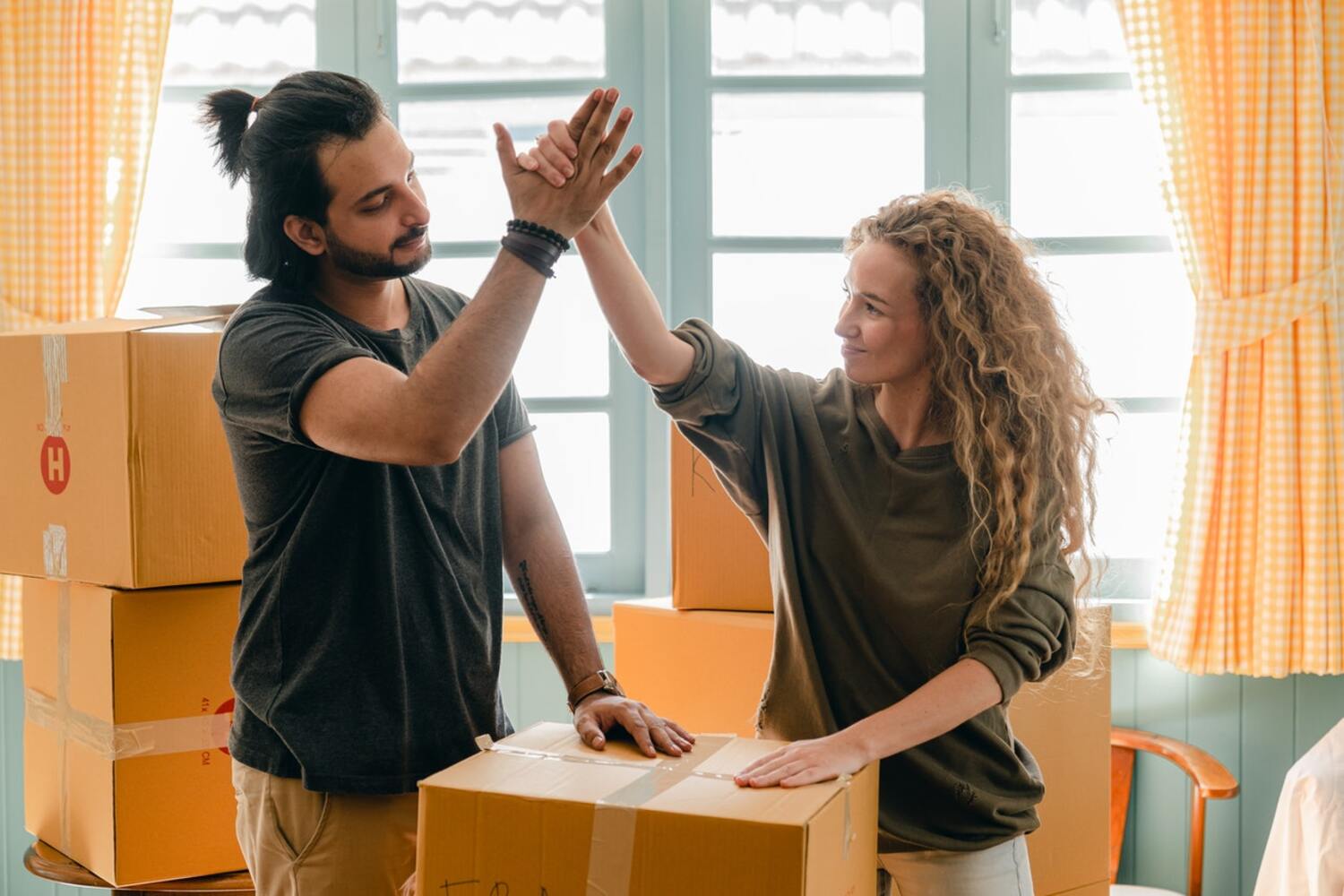 A Happy Couple packing boxes before buying a house.