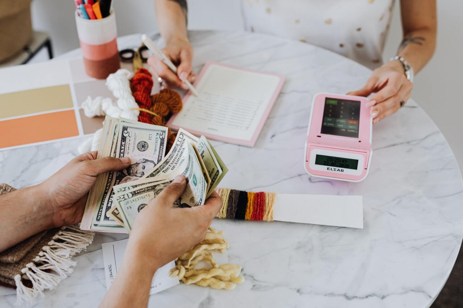 Two people counting money on a table that is residual income.