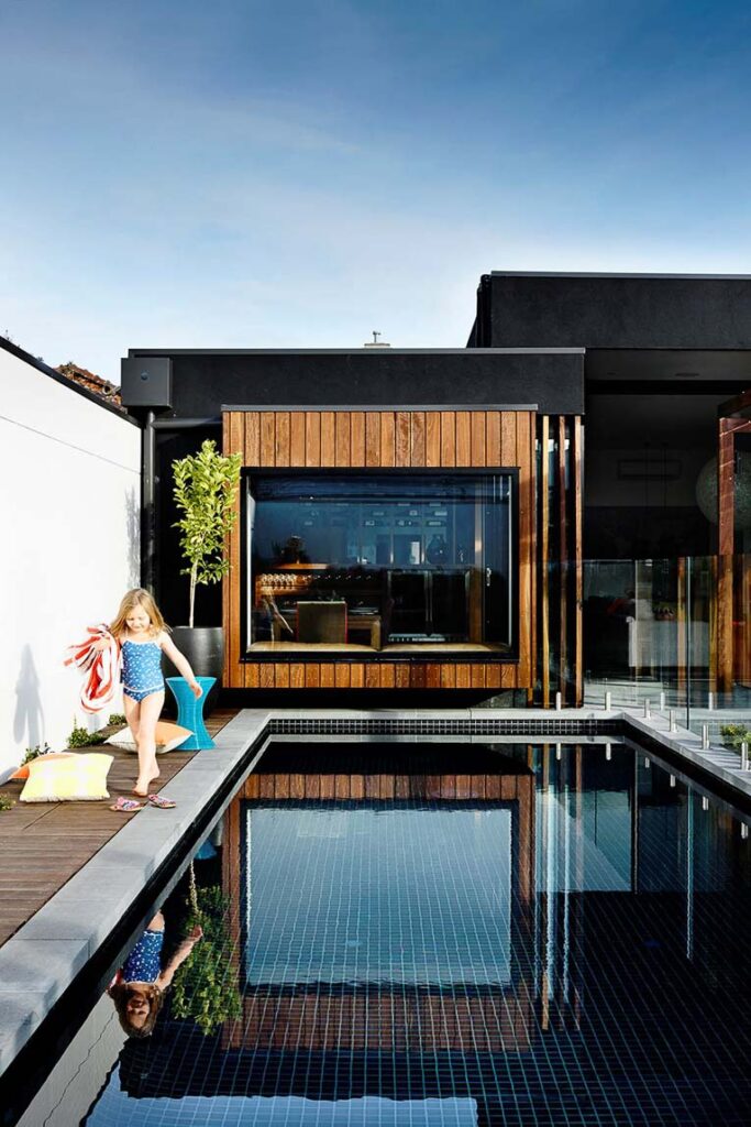 Modern house with a black pool and earthy elements.