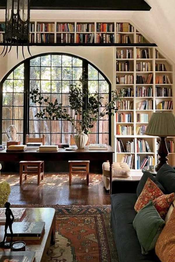 Two story wall with library bookshelves and arched window.