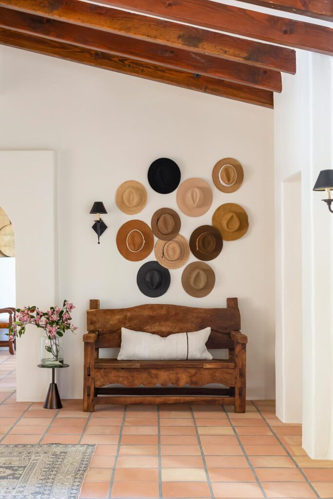 Hats hung on a wall over a mud bench in Spanish style home.