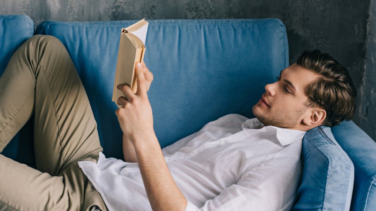 man laying down reading a book