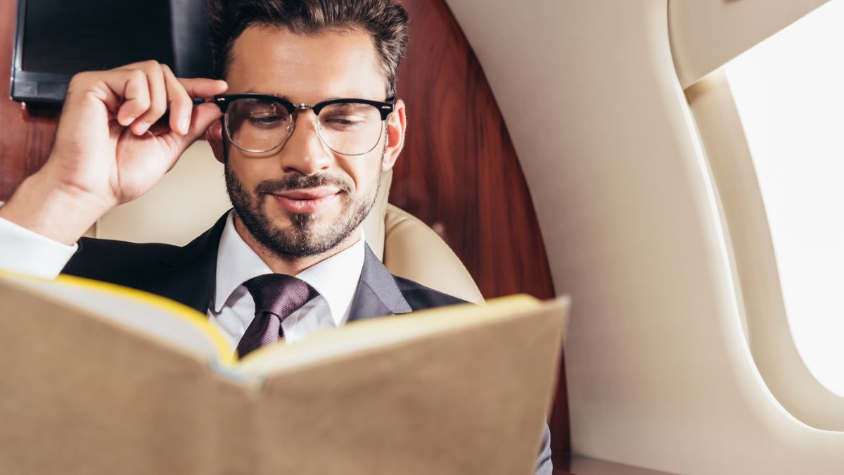 man with glasses and suit reading a book