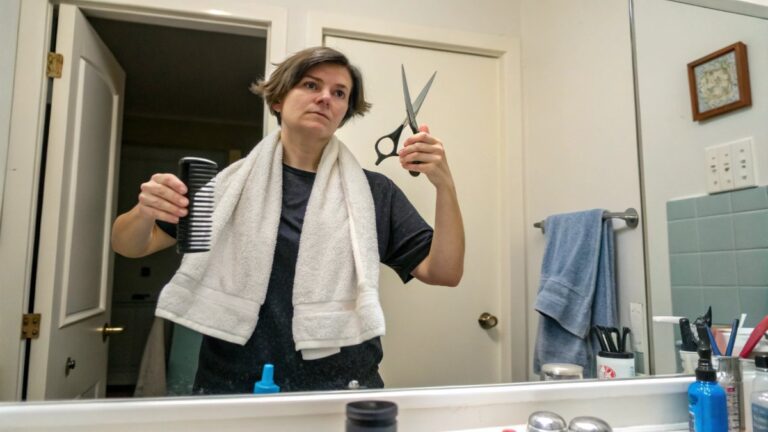 A person standing in front of a bathroom mirror with a towel draped over their shoulders