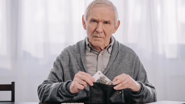 Male pensioner sitting at table and putting