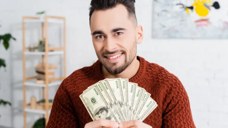 Cheerful bookmaker looking at camera and showing dollar