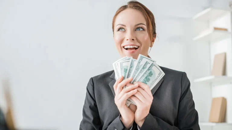 Happy financier holding dollar banknotes in office