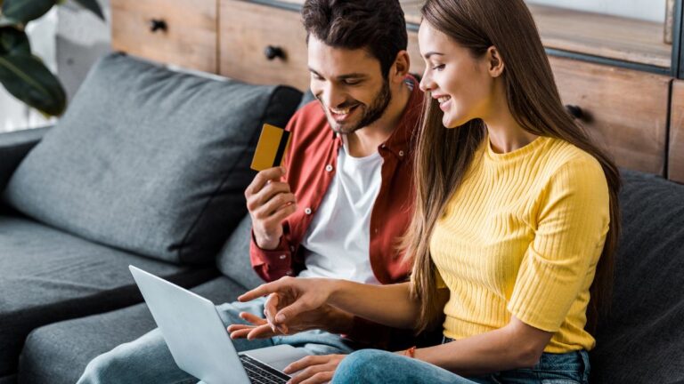 Happy man holding credit card and doing online