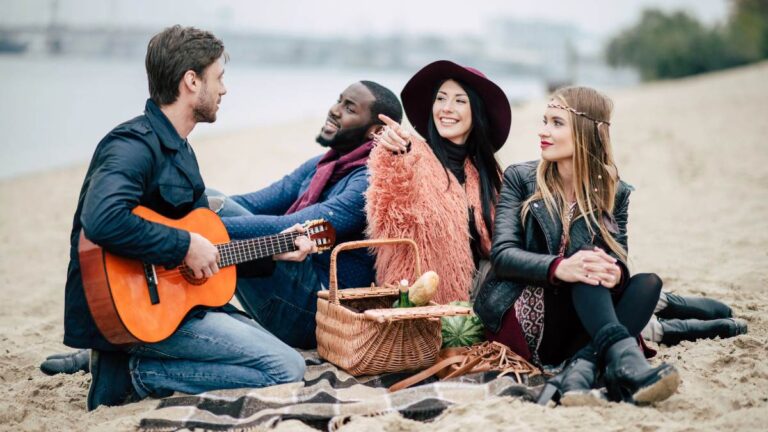 Happy young friends with guitar at picnic