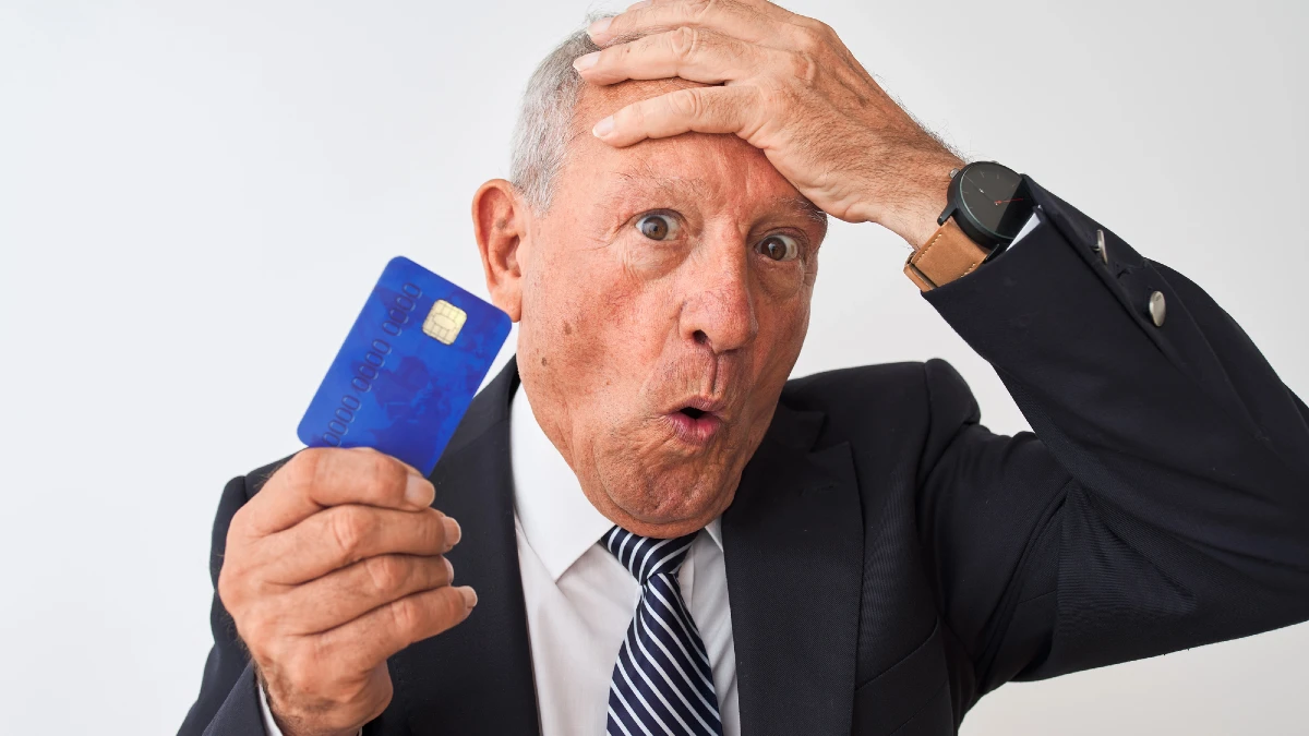 Senior grey-haired businessman holding credit card