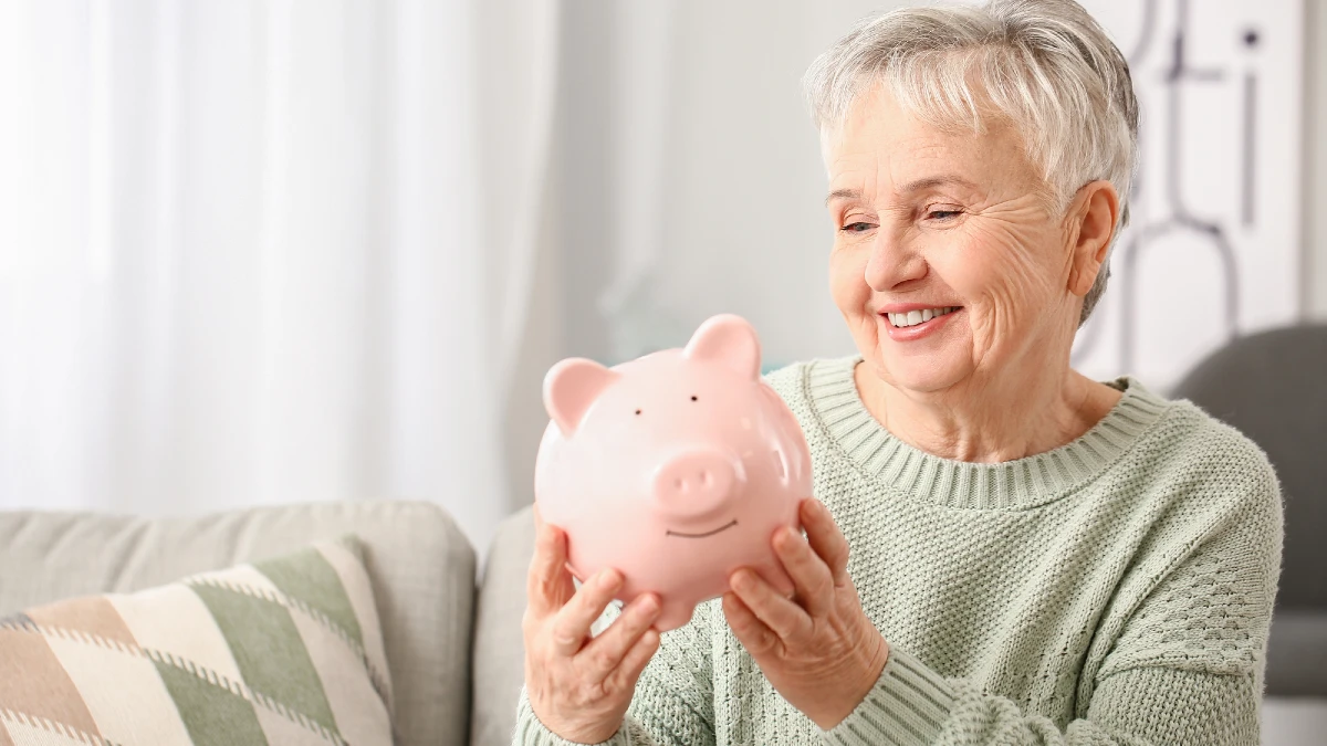 Senior woman with piggy bank at home