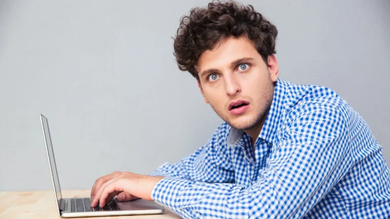 Shocked man sitting at the table with laptop