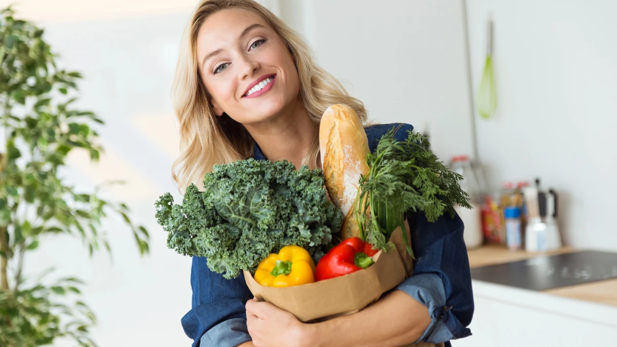 Beautiful young woman grocery shopping bag with vegetables