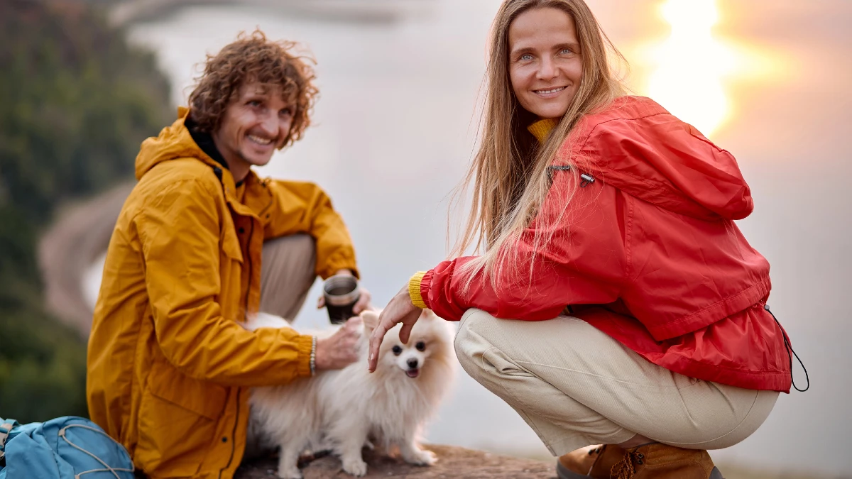 Cheerful couple with pet dog Hiking in mountains together