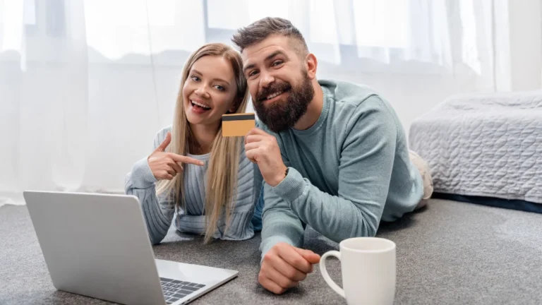 Happy couple lying on floor with laptop and shopping online