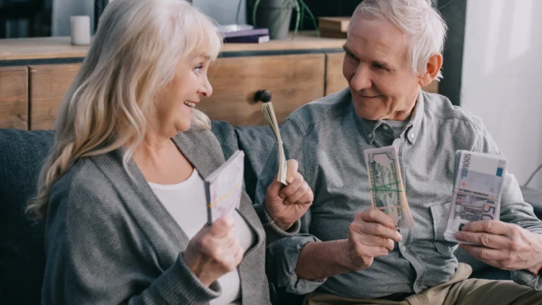 Happy senior couple sitting on couch and holding