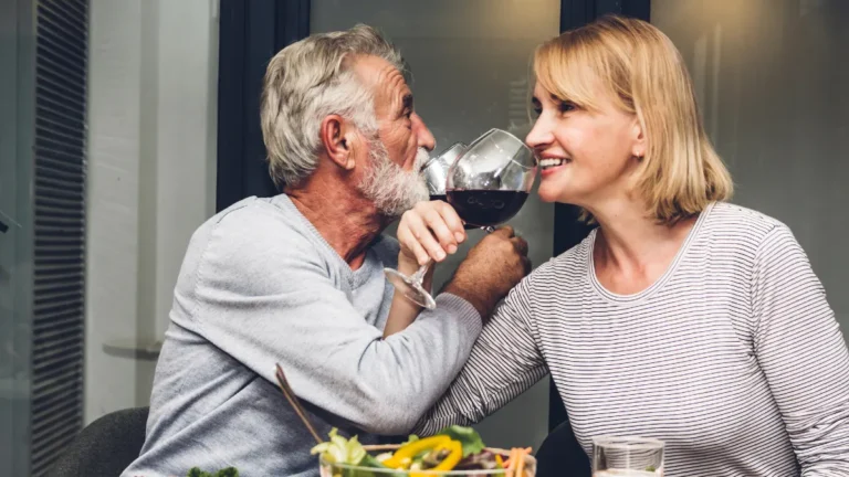 Happy smiling elder senior couple eating dinner and drinking win