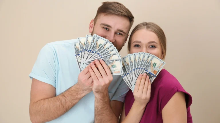 Happy young couple with money on color background