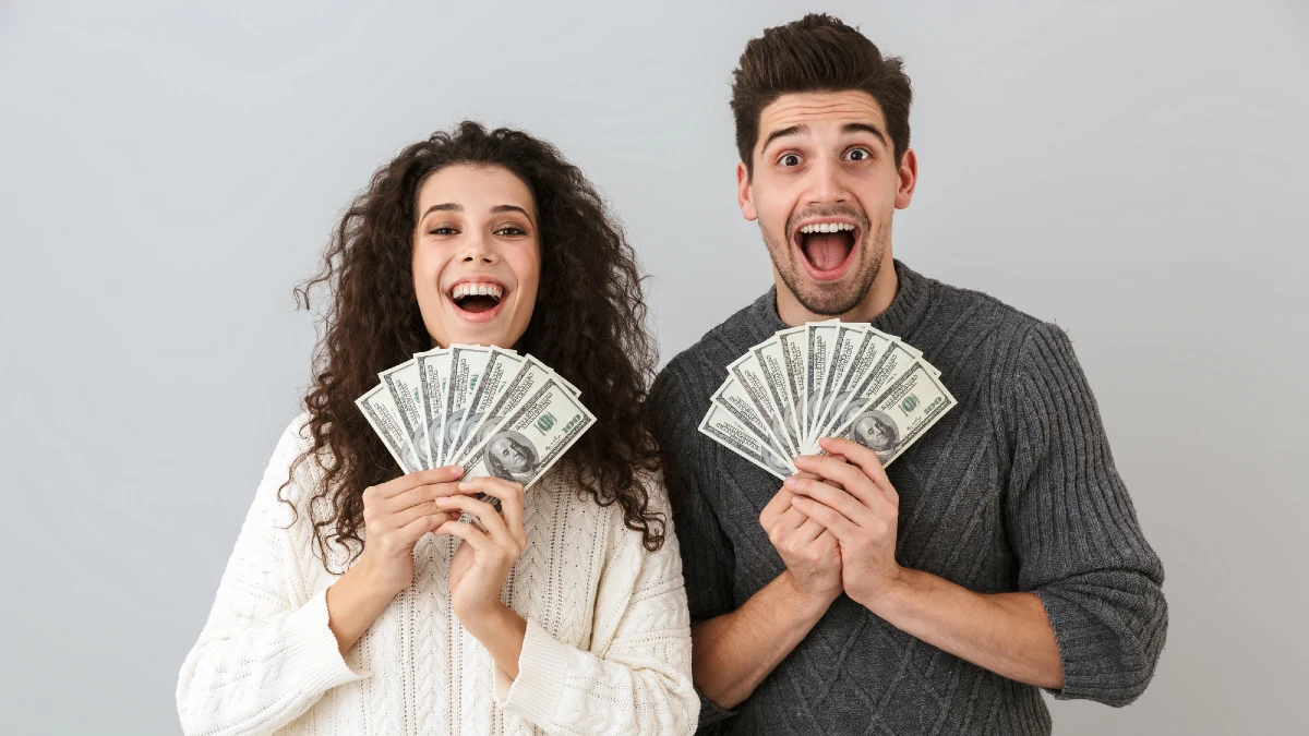 Image of happy man and woman holding fan of dollar