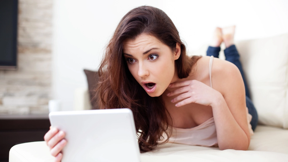 Surprised woman with tablet on couch