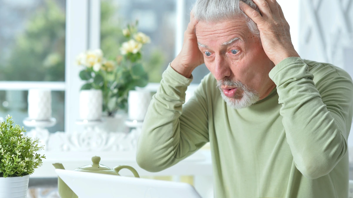 Emotional senior man using laptop at home